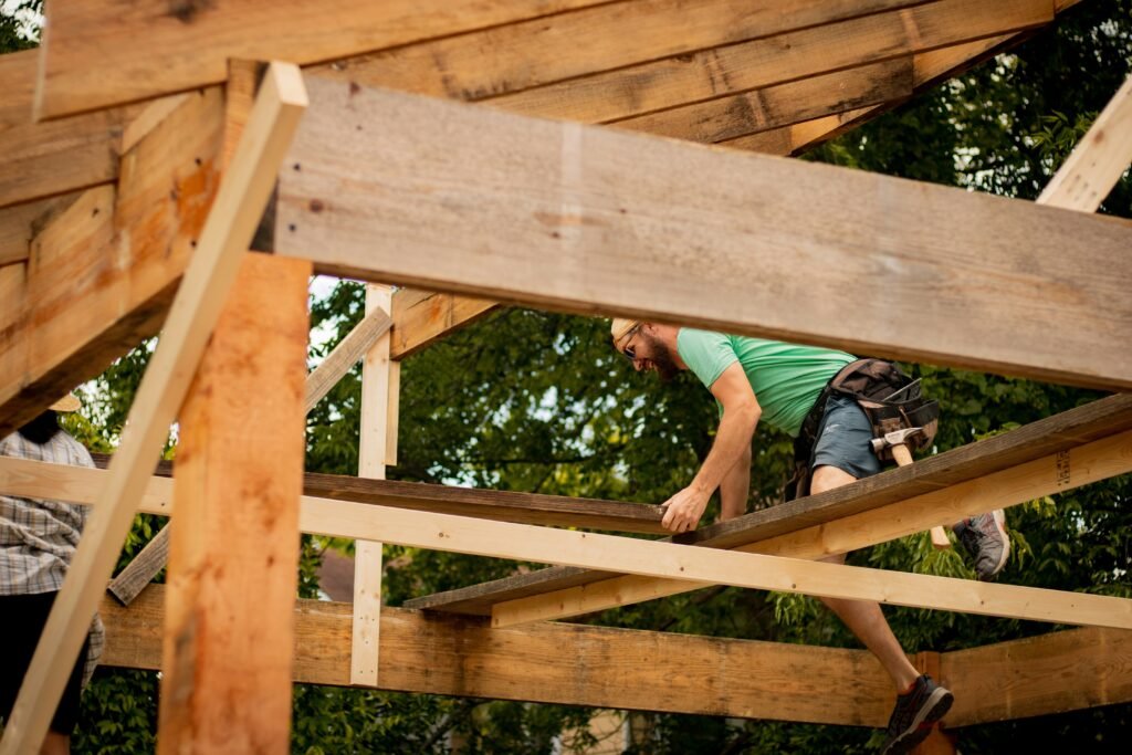 Person working on a wooden frame structure with basic tools