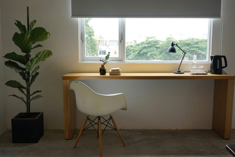 Minimalist home office with wooden desk by the window and white chair