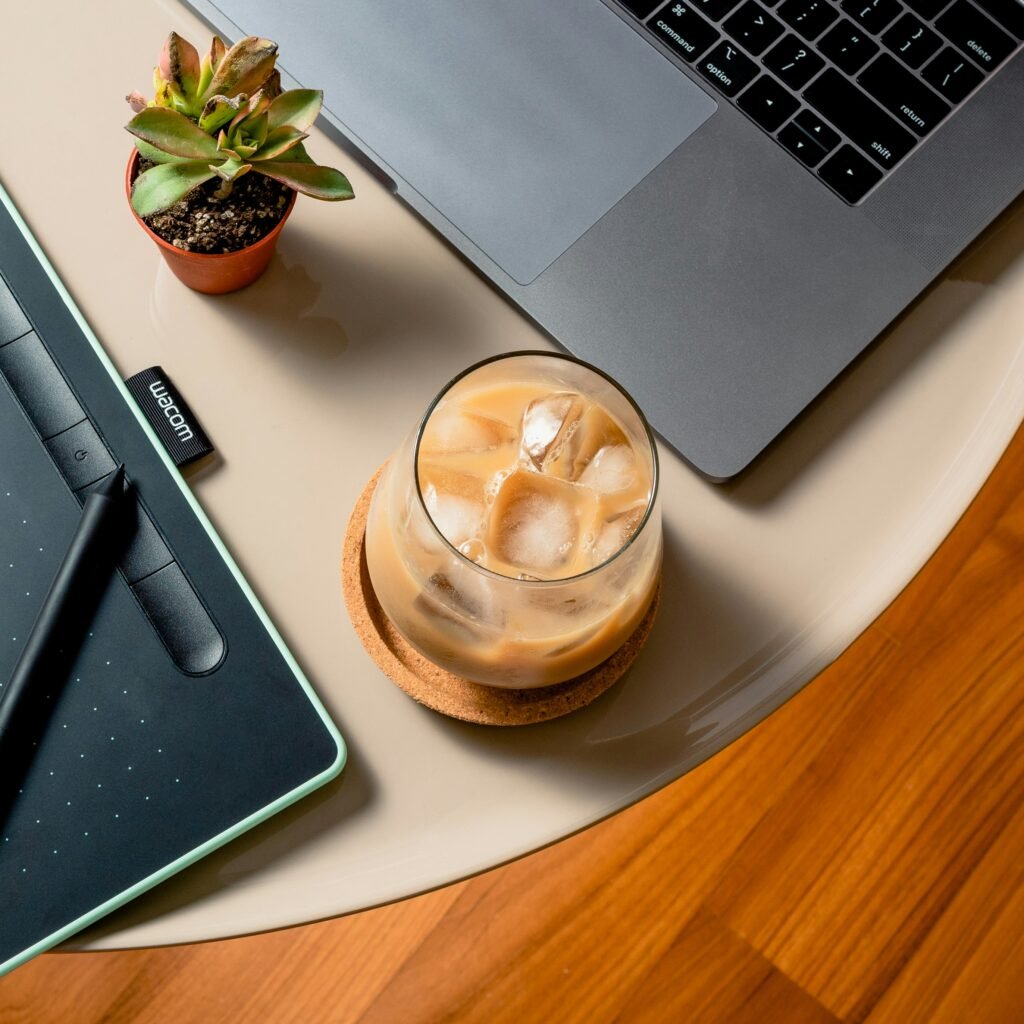 Laptop and iced coffee on wooden desk for creative content work