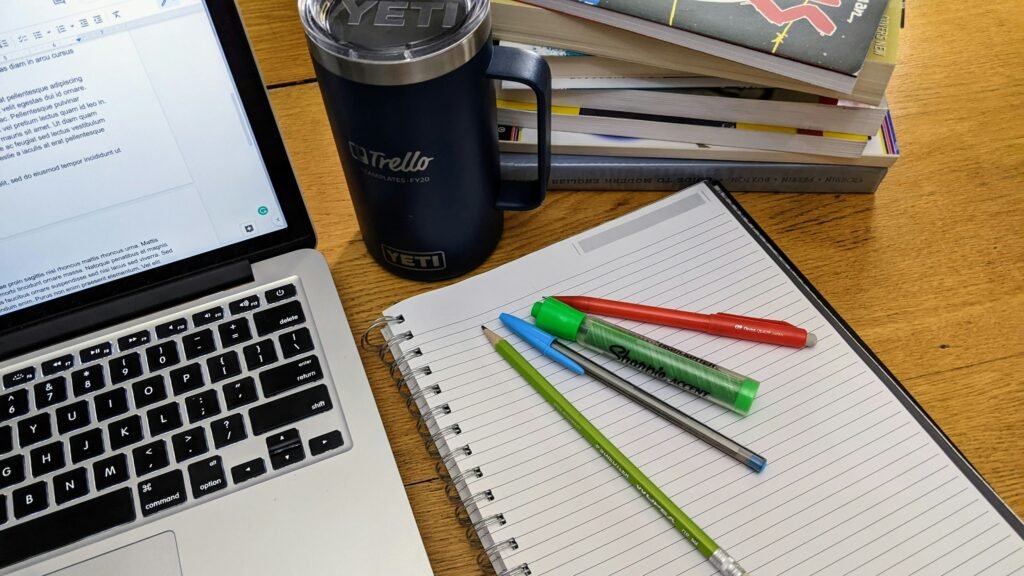 Laptop with notebook and pens on a minimalist desk