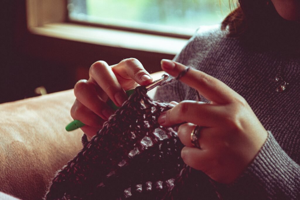 Hands knitting with yarn and needles on a wooden table