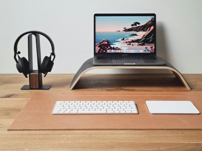 Minimal workspace with laptop, keyboard, and headphones on a wooden desk