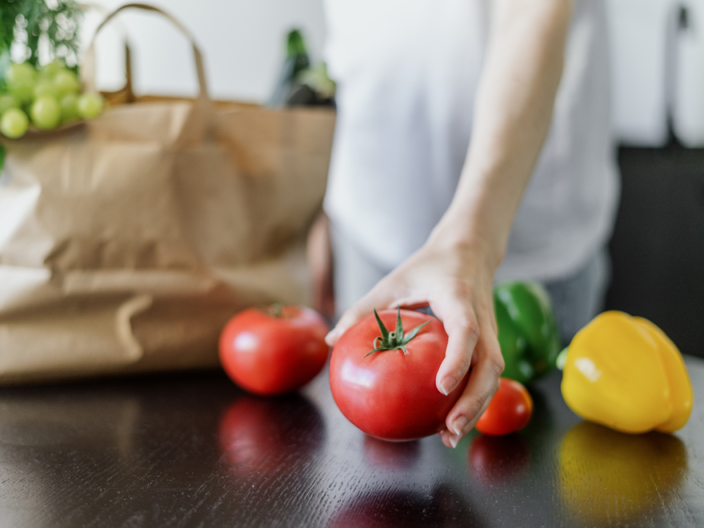 Minimalist grocery shopping in a store aisle with a tote bag and a small selection of fresh ingredients.